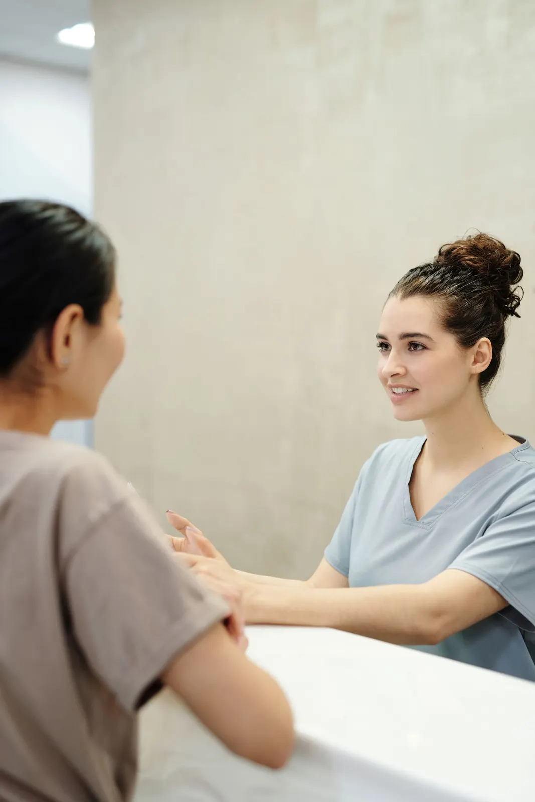 A patient and healthcare professional talking across a reception desk