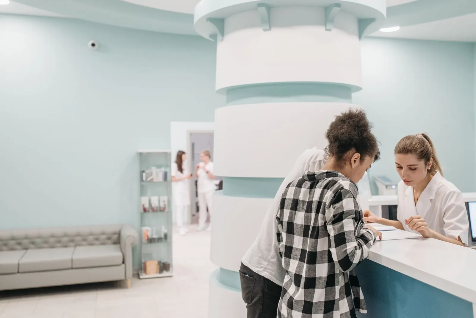 A patient speaking with a clinician at a bright medical reception desk